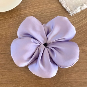 Vue détaillée d'un chouchou fleur en satin violet sur une table en bois rustique