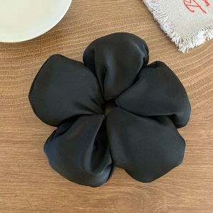 Gros plan détaillé d'un grand chouchou fleur en tissu noir sur une table en bois