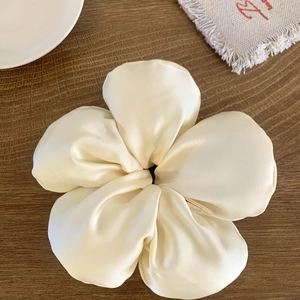 Détail macro d'un chouchou floral en satin crème sur un fond en bois sombre élégant