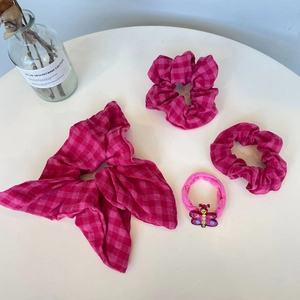 Detailansicht der rosa karierten Haargummis mit Schleife und Schmetterlingsanhänger