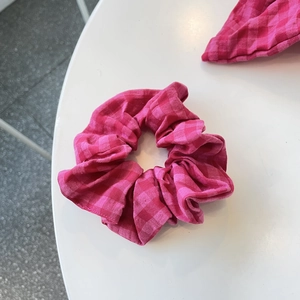Detailansicht des rosa karierten Gingham-Stoffs und der Baumwolltextur des Haargummis