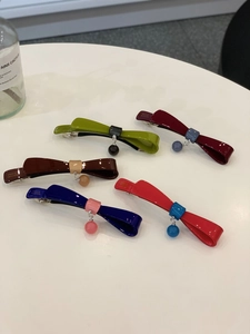 Dettaglio di fermagli per capelli a fiocco in resina colorata con ciondoli a sfera e clip