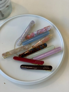 Detail shot of colorful acetate barrettes with floral and marble patterns in a ceramic dish