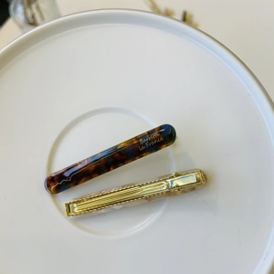 Macro detail of thick tortoiseshell and marble patterned hair clips on white ceramic