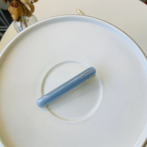 Detail of blue acrylic duckbill hair clip with golden Barrette La France lettering