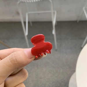 Vue détaillée d'une pince à cheveux en acétate rouge brillant au fini glacé