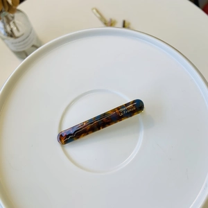 Detail of French style tortoiseshell hair clip with gold lettering on white plate