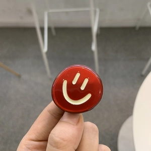 Vue macro d'une pince à cheveux ronde rouge brillante avec un motif de smiley blanc