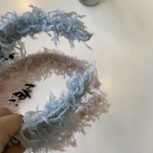 Detail of fluffy fairy-style feather headbands in light blue, pink and black colors