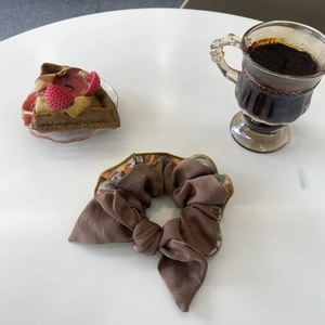 Vue détaillée d'un chouchou léopard marron à fleurs avec nœud sur une table de café