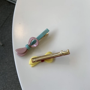 Detail of pink and yellow handmade bow hair clips with gold metal base and resin finish