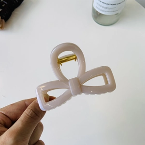 Close-up of the elegant matte bow hair claw clip in soft pink with a gold spring