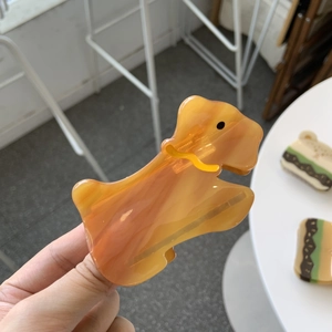 Détail de la pince à cheveux en acétate orange en forme d'éléphant avec texture marbrée