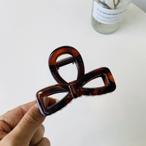 Detail of tortoise shell amber bow hair claw clip with sturdy black metal spring