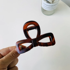 Macro shot of a dark tortoiseshell bow hair claw clip with a glossy acetate finish