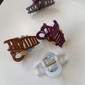 Detail of four colorful geometric hair claw clips with resin beads and metal springs