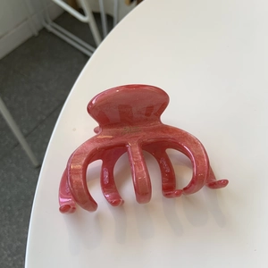 Détail de la pince à cheveux rose pailletée avec lettrage doré et ressort en métal