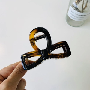 Detail of tortoise shell bow hair claw clip made of amber acrylic with sturdy metal spring