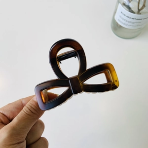 Detail of a large dark brown tortoiseshell butterfly hair claw clip held by hand