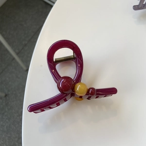 Detail view of a purple hair claw clip with yellow and purple beads and metal spring