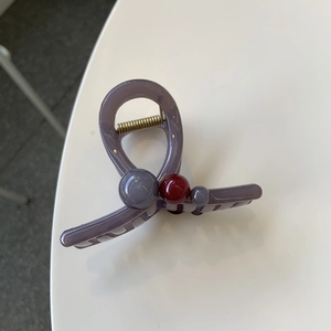 Detail view of purple-grey acrylic hair claw clip with beads and gold metal spring