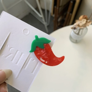 Red chili pepper hair clip made of acetate resin on display card with hand