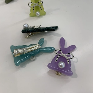 Dettaglio di fermagli per capelli a coniglio colorati con fiocchi e perle