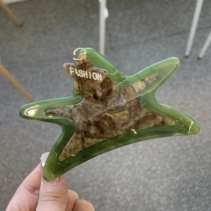 Detail of star-shaped acetate hair claw clip with green marble pattern and FASHION text
