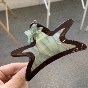 Detail of star-shaped acetate hair claw clip featuring green texture and fashion pendant