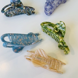 Detailed top view of five large acetate hair claw clips in various marble patterns