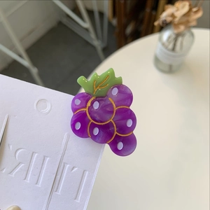 Close-up of purple grape hair clip with green leaves and gold edging on white card