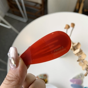 Détail d'une barrette goutte en acétate rouge avec inscription France Handmade dorée