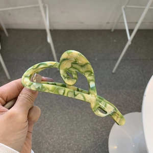 Elegant marble pattern acetate hair claw clip with a green and yellow wavy streamlined design