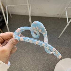 Detail showing the blue and pink marbled acetate hair claw with heart cutout design