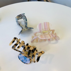 Three acetate octopus hair claws featuring marble blue, pink stripes, and tortoiseshell patterns