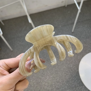 Octopus claw clip with beige marble pattern for thick hair, holding style presentation