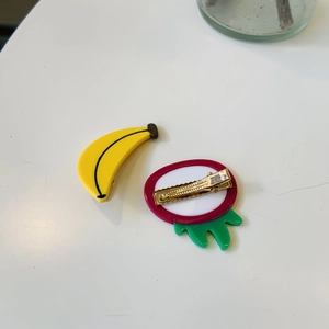 Detail view of the colorful fruit-shaped acetate hair clips with a sturdy gold metal duckbill base