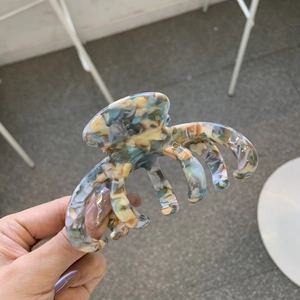Close-up of a large tortoiseshell acetate claw clip with colorful marble patterns
