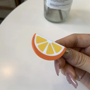 Vibrant orange slice hair clip made of glossy acrylic with realistic fruit patterns