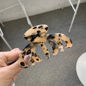 Detail showing high-quality beige tortoiseshell acetate hair claw clip held by hand