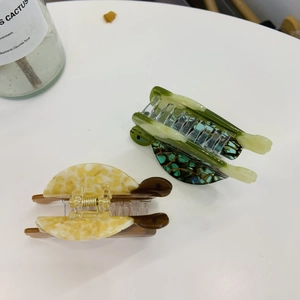Ocean-inspired tortoise shaped acetate hair claws in dark green and yellow tortoiseshell pattern