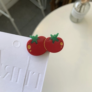 Detailed macro view of the glossy tomato-shaped hair clip with gold polka dots