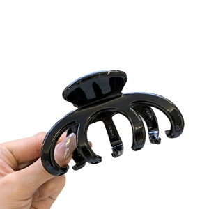 Glossy black acetate octopus hair claw clip with golden label for women stylish look