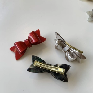 Detailed macro view showing acetate bow hair clips with metal duckbill clasp and marble pattern