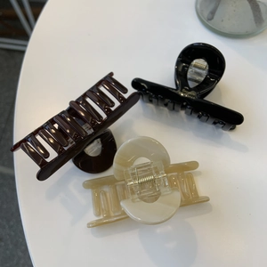 Detail showing high-gloss hair claws in black, tortoise and cream with gold springs