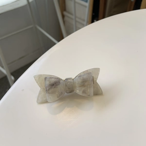 Detailed close-up of marble pattern acetate hair clip with engraved handmade logo