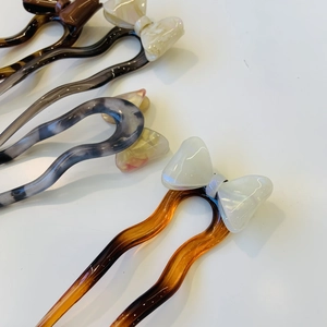 Détails d'épingles à cheveux en acétate en forme de U avec design ondulé et nœud élégant