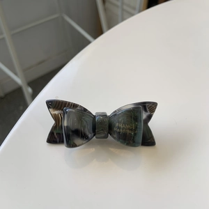 Detail of handmade acetate hair clip featuring dark green tortoise shell bow pattern