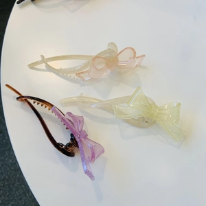 Trois barrettes nœuds translucides aux couleurs bonbon rose, jaune et violette sur blanc