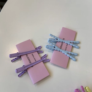 Dettaglio di fermagli per capelli ondulati color pastello su scheda rosa a mano